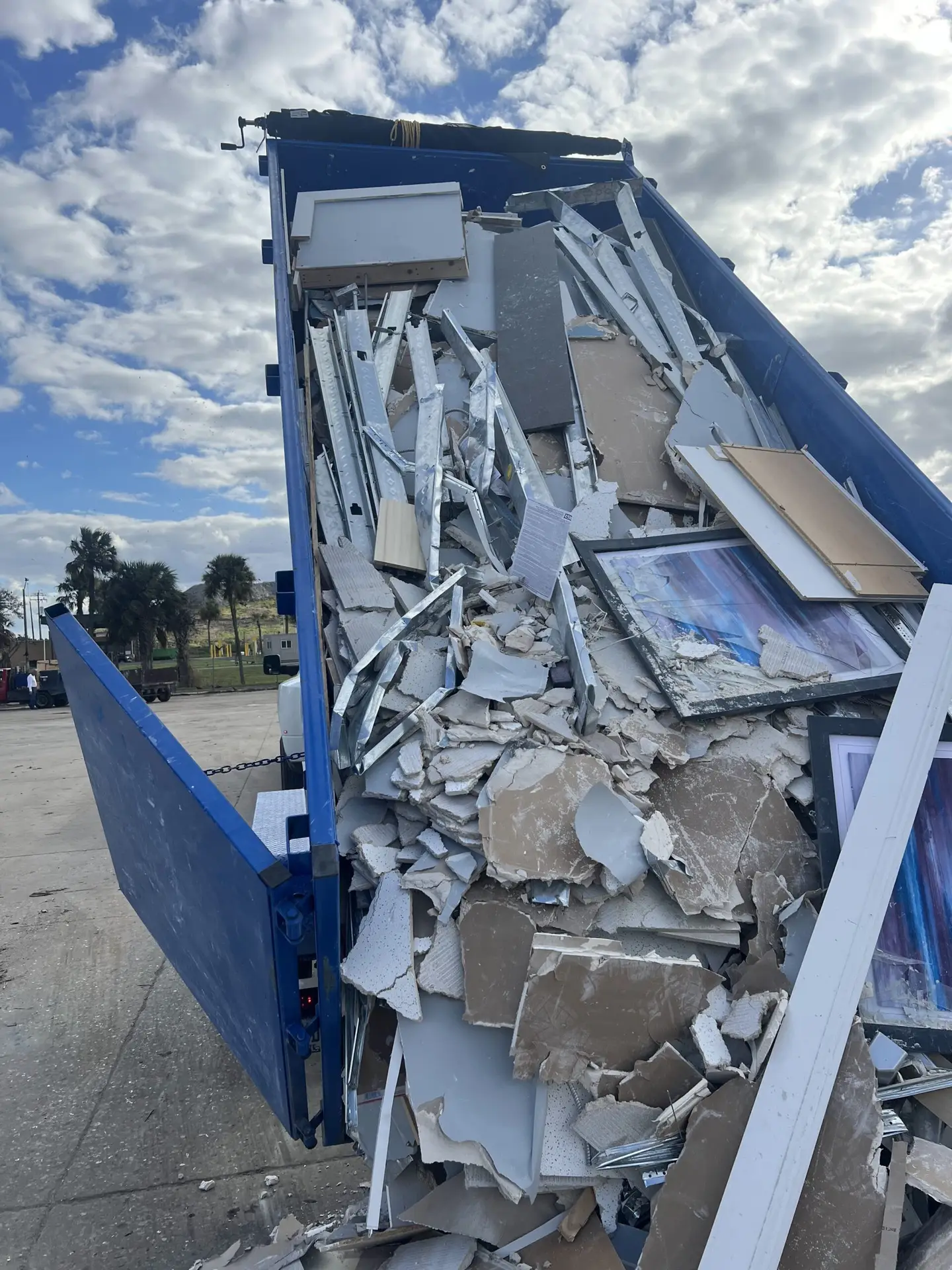 Construction debris being unloaded from a blue 17-yard dump trailer in Palm Beach County, FL.